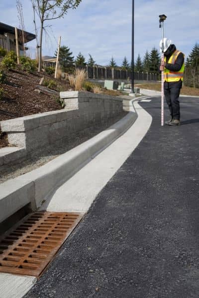 Surveyor measuring finished grades and completed site features after construction