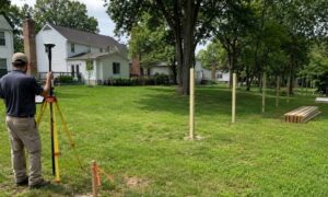 A surveyor completes a boundary survey in a Maryland backyard before new fence posts are installed