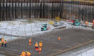 Workers reinforcing a building foundation as a construction survey helps verify column layout before concrete is poured