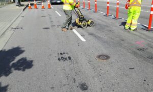 Workers locating underground utilities for an ALTA survey utilities assessment at a commercial site