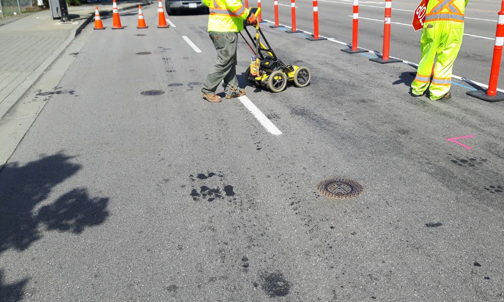 Workers locating underground utilities for an ALTA survey utilities assessment at a commercial site