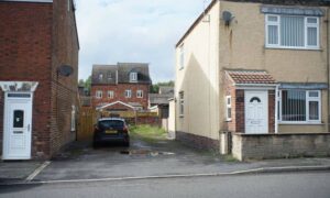 Narrow driveway between two houses leading to a rear parking area, illustrating the access layout relevant to a subdivision survey